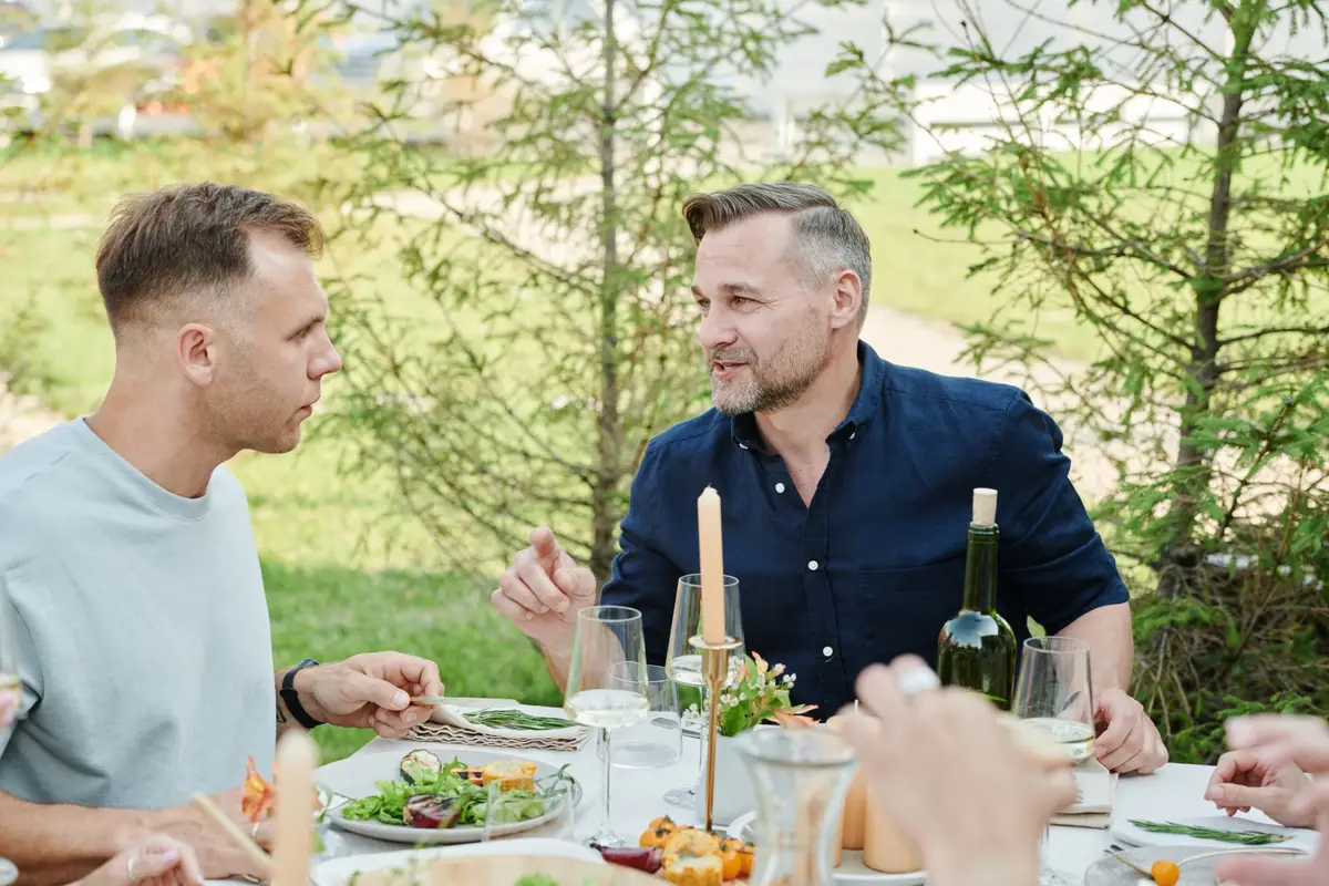Amigos conversando durante uma refeição simples ao ar livre, lembrando o Jardim de Epicuro