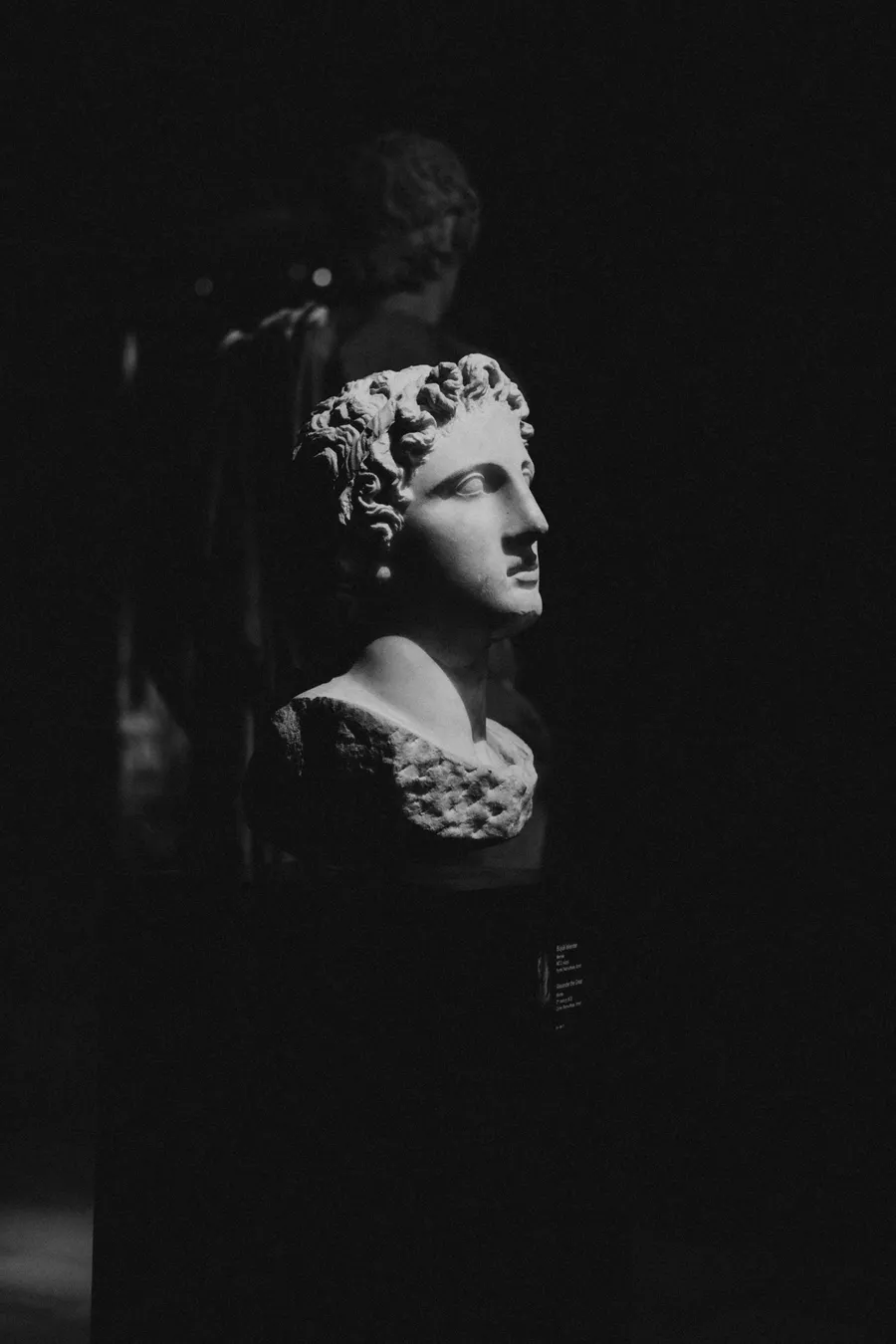 Busto romano de mármore iluminado sobre fundo escuro
