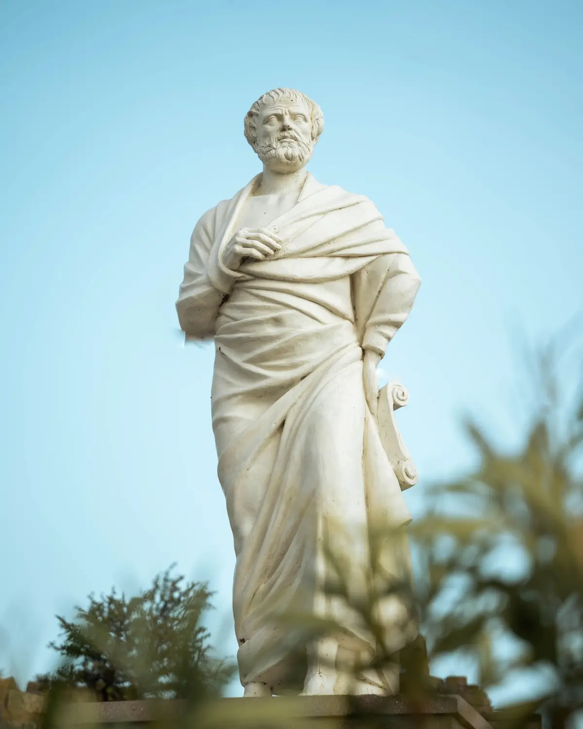 Estátua de mármore de um filósofo grego ao ar livre, tema de estoicismo x epicurismo