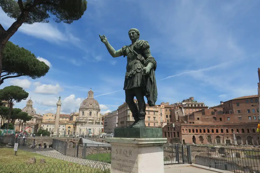 Estátua de bronze romana diante de igrejas e prédios históricos de Roma