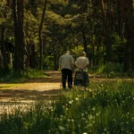 Casal de idosos caminhando de mãos dadas num caminho da floresta, tema de estoicismo e envelhecimento