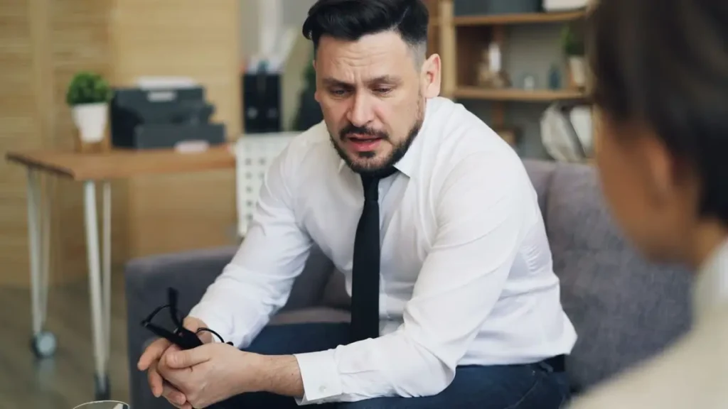 Homem numa conversa séria e calma no sofá, tema de estoicismo e relacionamentos