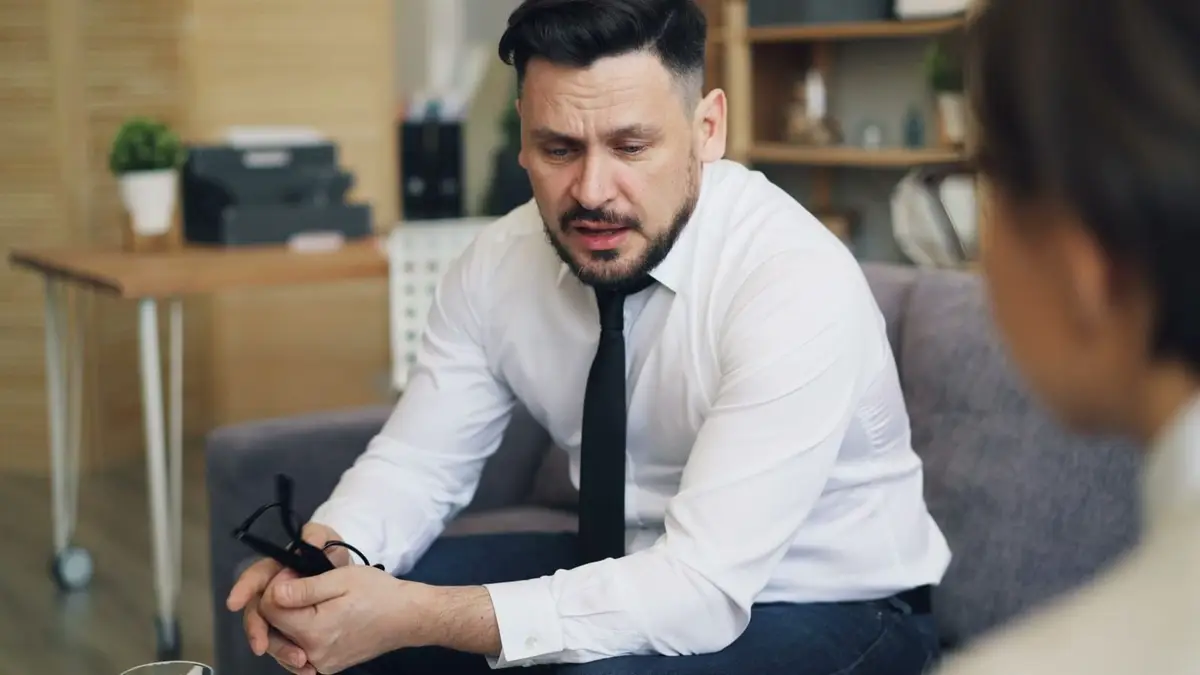 Homem numa conversa séria e calma no sofá, tema de estoicismo e relacionamentos