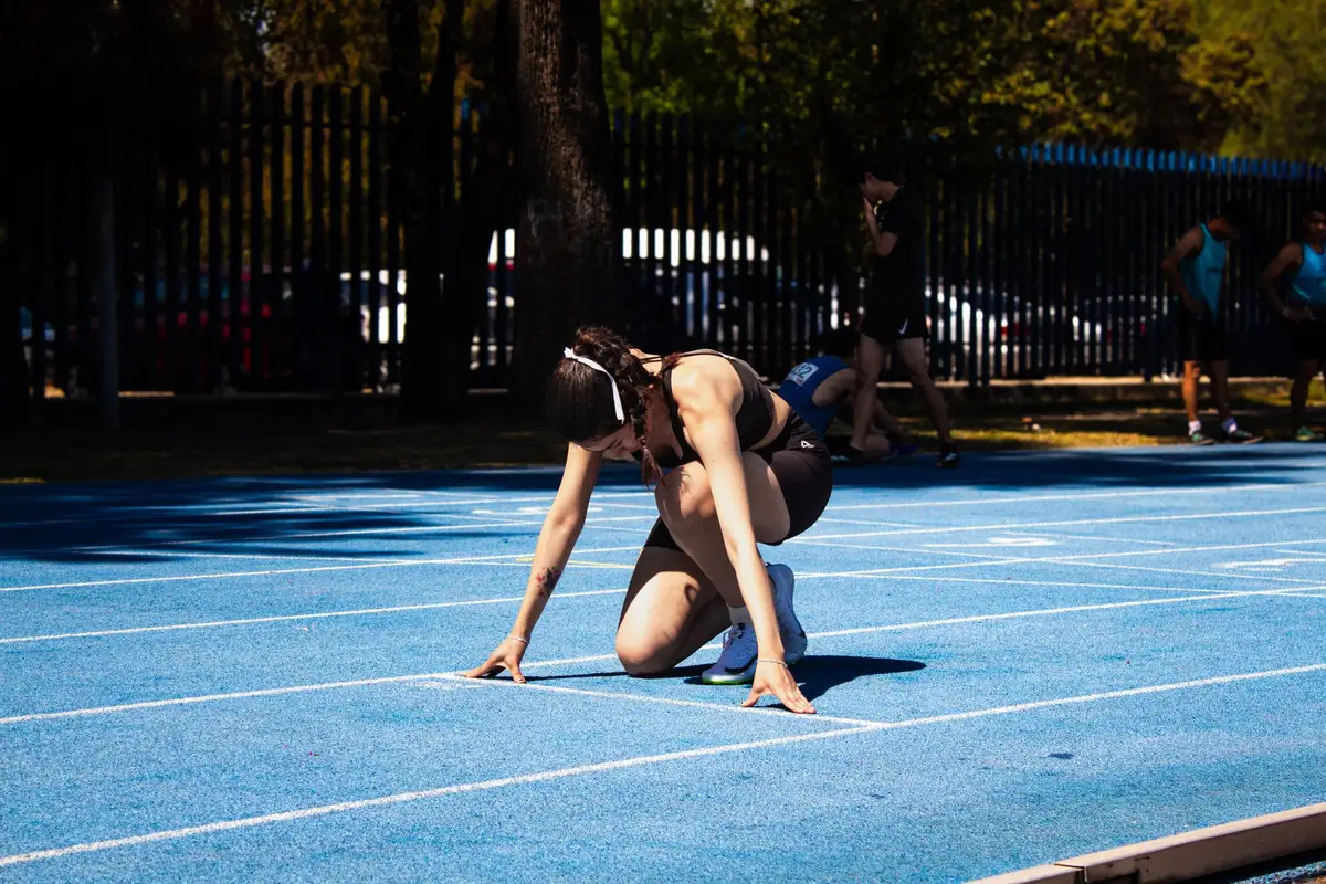 Atleta concentrada na largada de uma pista de corrida, tema de estoicismo no esporte