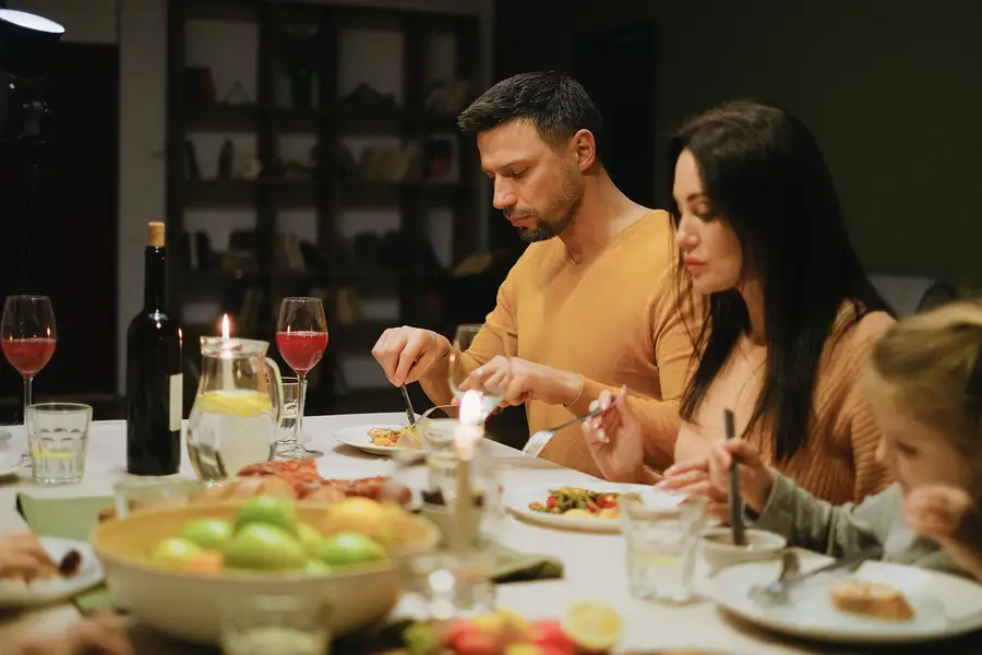 Família jantando junta à luz de velas, o círculo mais próximo de cada pessoa