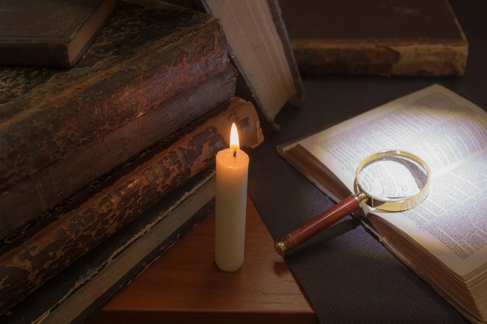Livros antigos, vela e lupa sobre a mesa, representando as frases de Sêneca