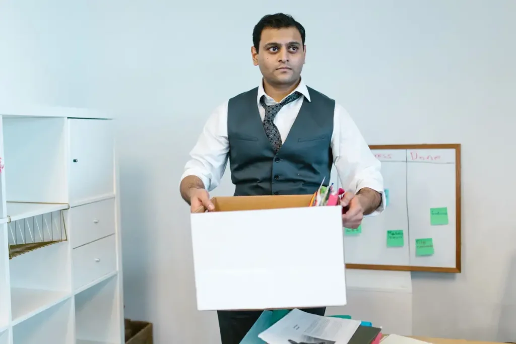 Homem saindo do escritório com seus objetos numa caixa de papelão