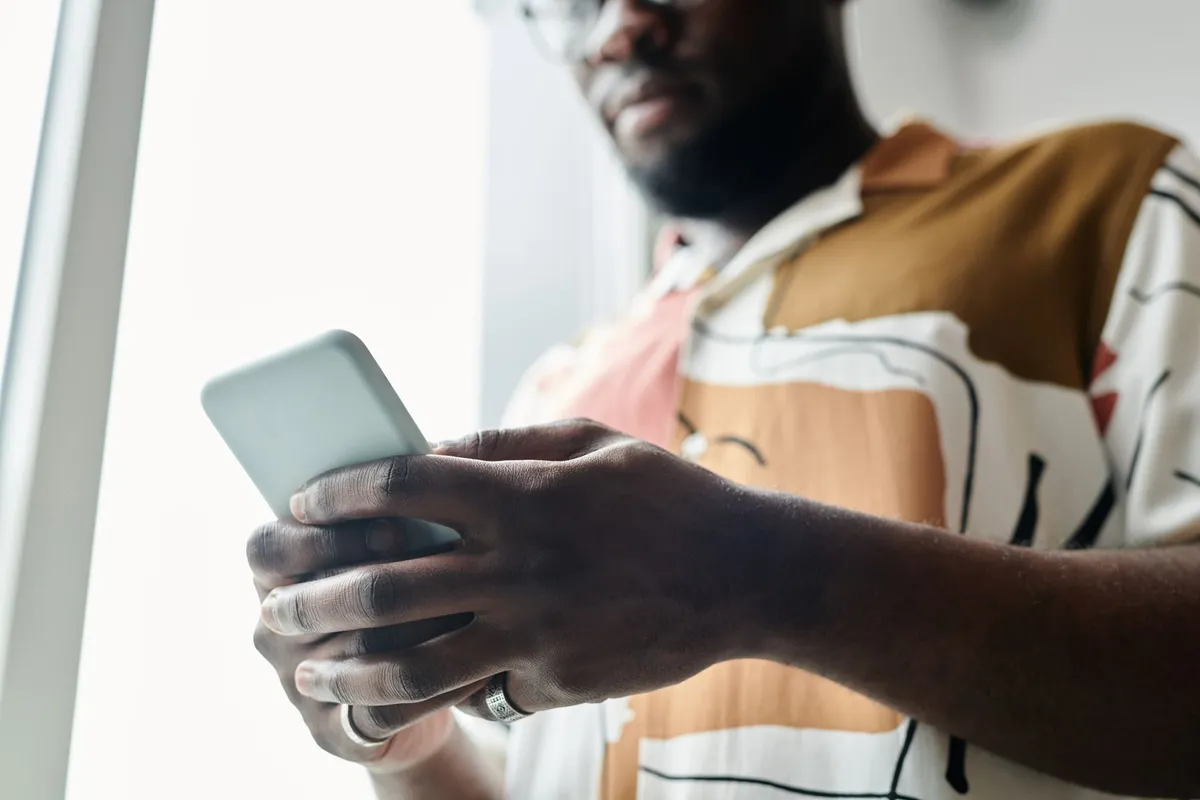 Homem lendo comentários no celular perto da janela, aplicando estoicismo e redes sociais