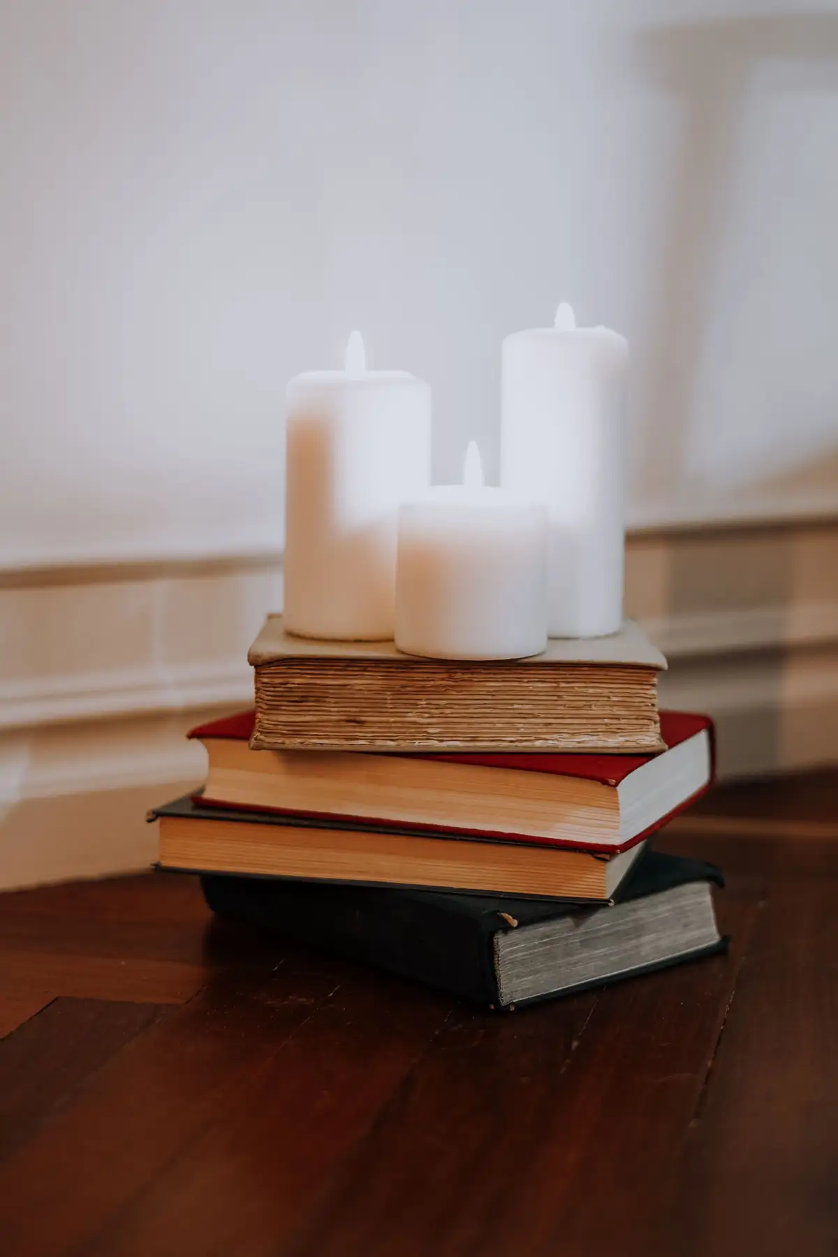 Livros empilhados e velas acesas sobre mesa de madeira