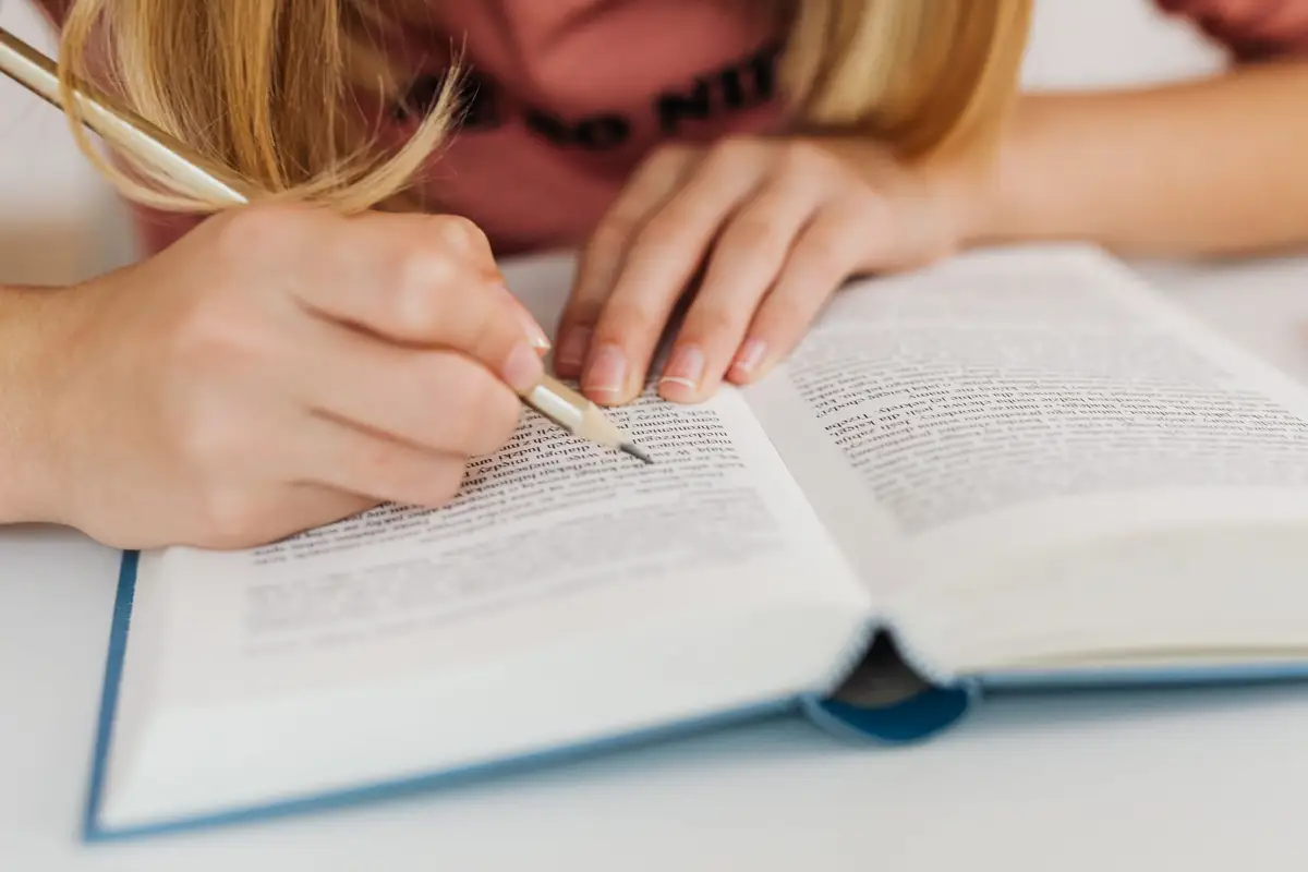 Mãos fazendo anotações com caneta nas páginas de um livro