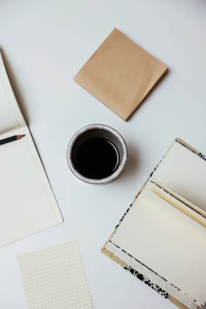 Mesa organizada com café, caderno aberto e anotações para começar a tarefa