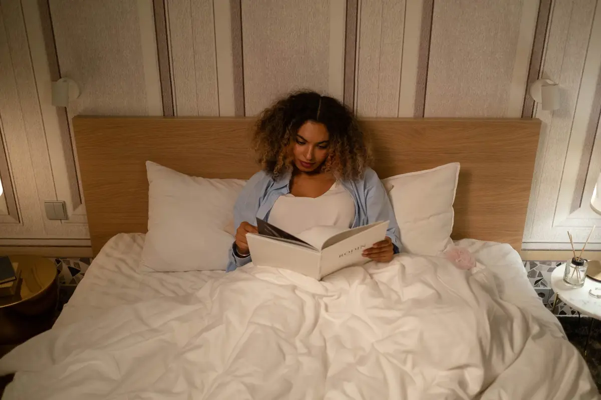 Mulher lendo um livro na cama antes de dormir, prática de estoicismo e insônia