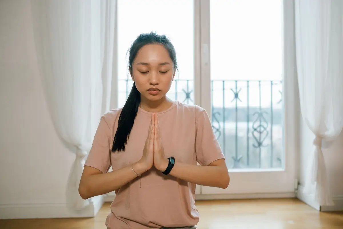 Mulher meditando de olhos fechados junto à janela, prática central do budismo na comparação estoicismo x budismo