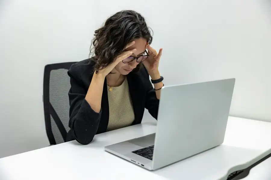 Mulher preocupada com a mão na cabeça diante do notebook