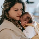 Mãe abraçando o bebê junto ao peito, imagem do cuidado natural que está na origem da oikeiosis