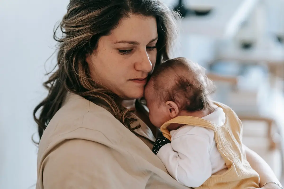 Mãe abraçando o bebê junto ao peito, imagem do cuidado natural que está na origem da oikeiosis