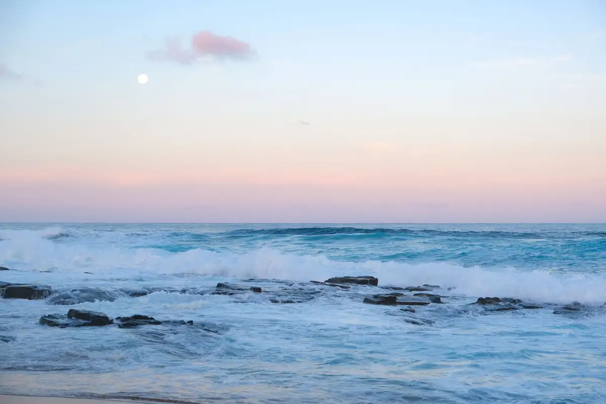 Ondas do mar quebrando nas rochas ao entardecer, fenômeno estudado por Posidônio