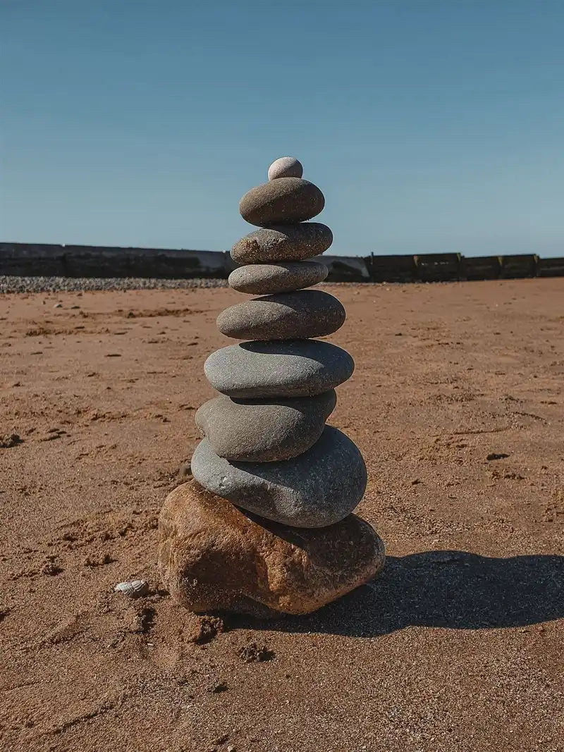 Pedras empilhadas em equilíbrio na areia, símbolo da prática constante