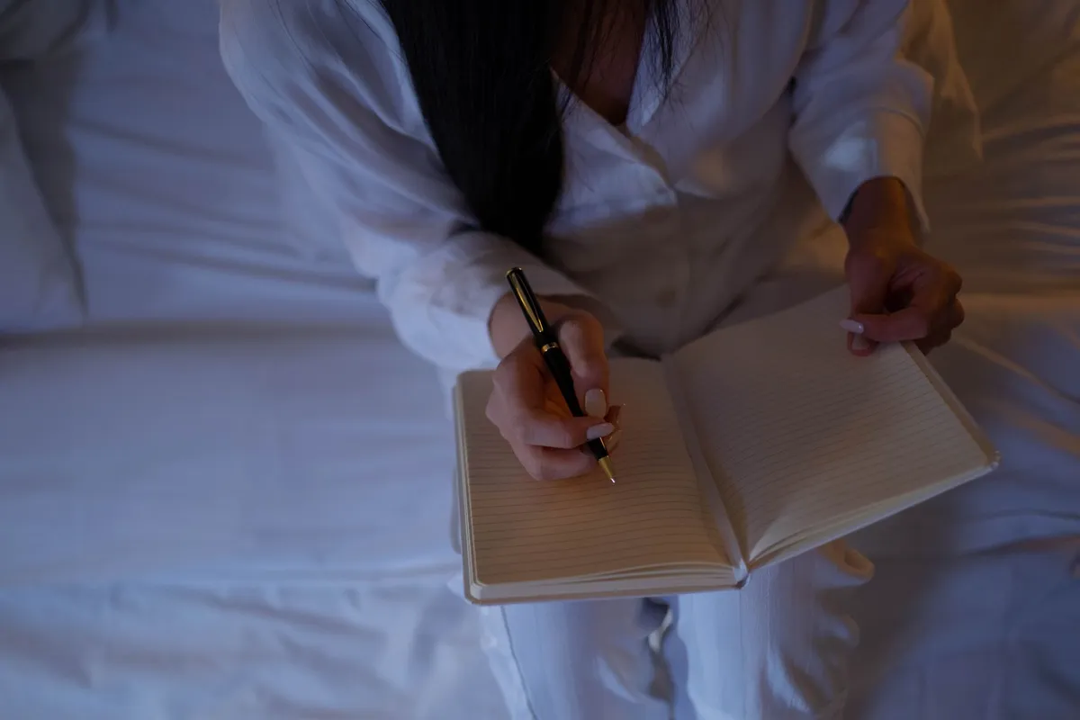 Pessoa escrevendo num caderno sentada na cama, prática de estoicismo e luto
