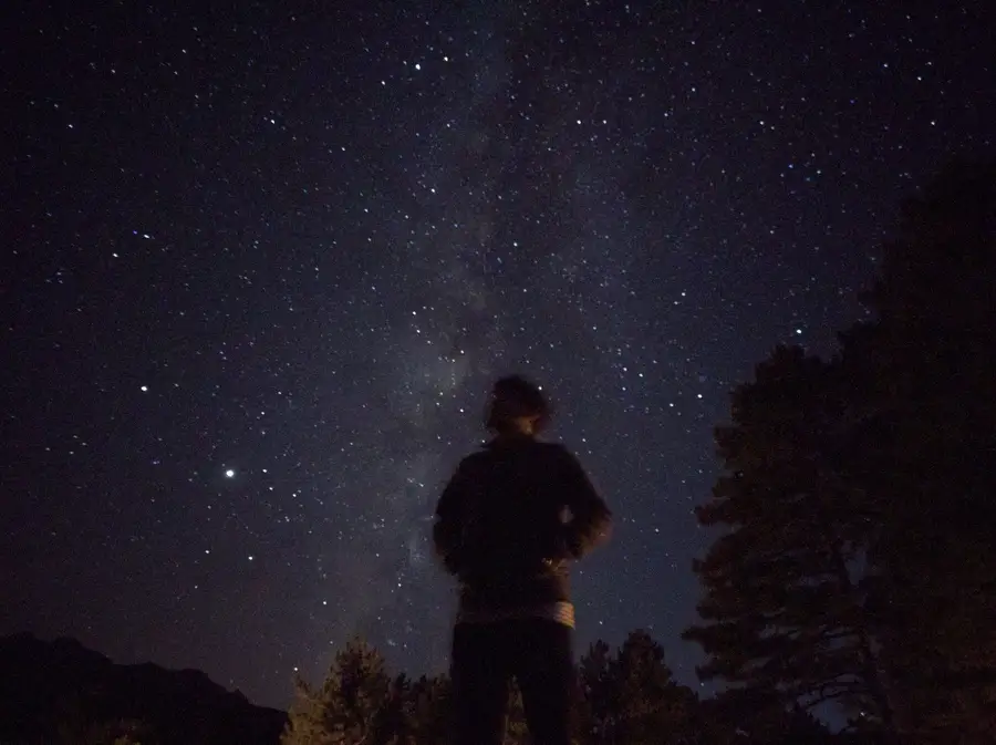 Pessoa olhando o céu estrelado à noite, imagem da ordem do universo no debate estoicismo x niilismo
