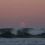 Lua nascendo sobre o oceano, lembrando os estudos de Posidônio sobre as marés
