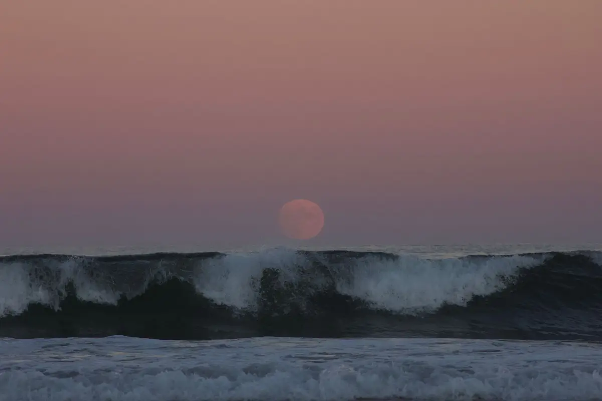 Lua nascendo sobre o oceano, lembrando os estudos de Posidônio sobre as marés