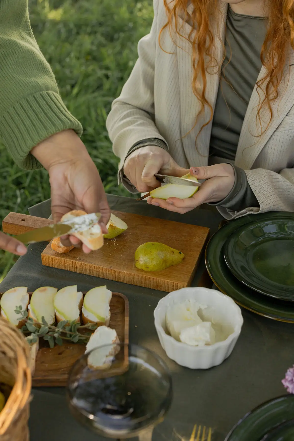 Mãos preparando comida simples com peras e queijo ao ar livre