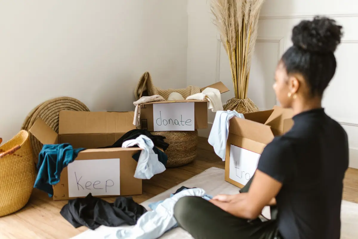 Mulher separando roupas em caixas para doar e guardar, prática de estoicismo e minimalismo