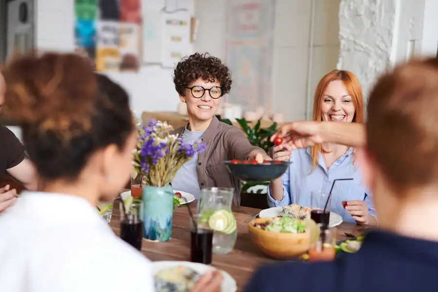 Amigos sorrindo e dividindo uma refeição em volta da mesa