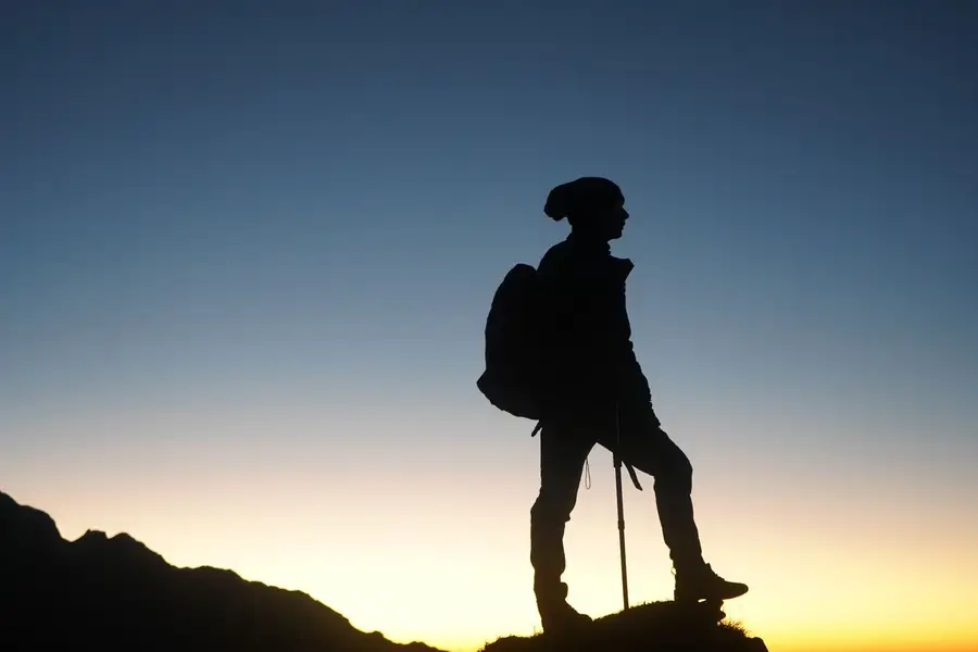 Silhueta de uma caminhante no alto da montanha ao amanhecer