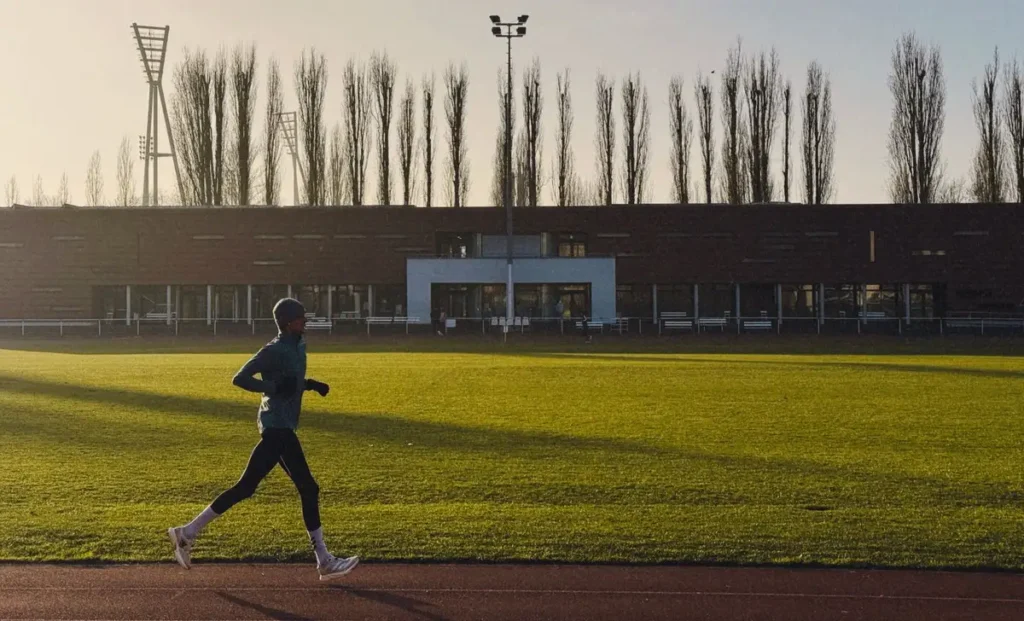 Homem correndo sozinho numa pista de atletismo ao amanhecer