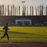 Homem correndo sozinho numa pista de atletismo ao amanhecer