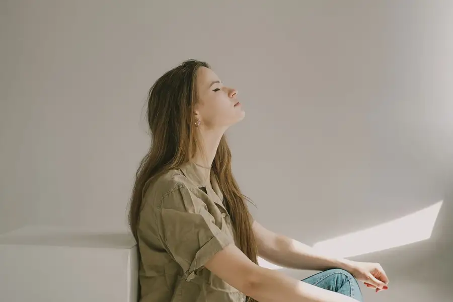 Mulher sentada de olhos fechados, refletindo com calma