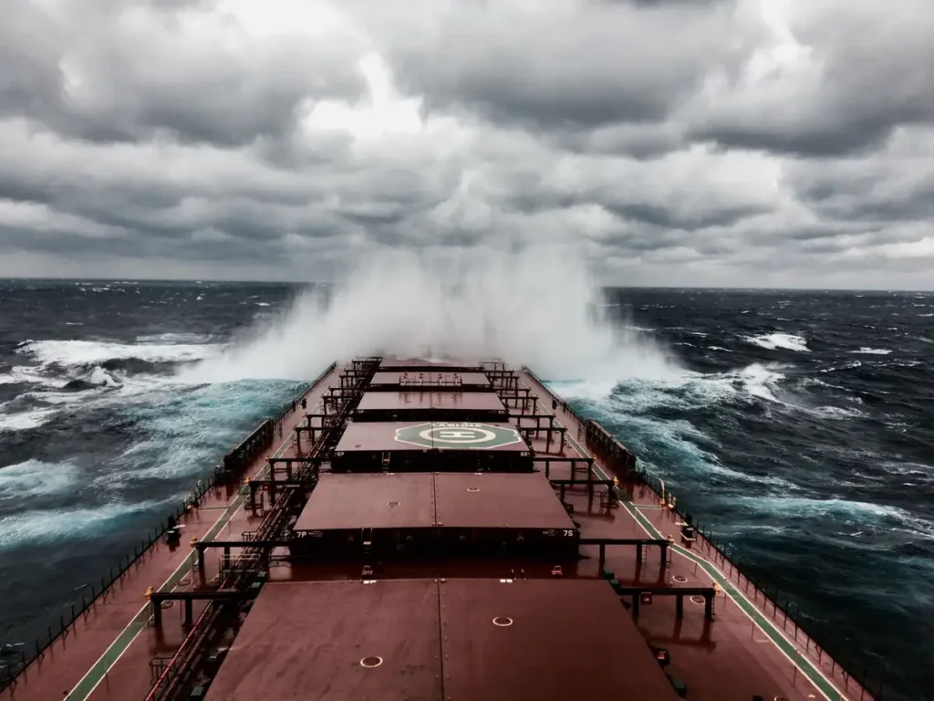 Navio enfrentando ondas fortes em mar agitado sob céu de tempestade