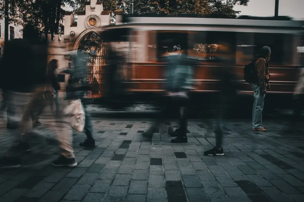 Pessoas apressadas caminhando numa rua da cidade enquanto o bonde passa