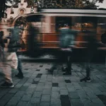 Pessoas apressadas caminhando numa rua da cidade enquanto o bonde passa