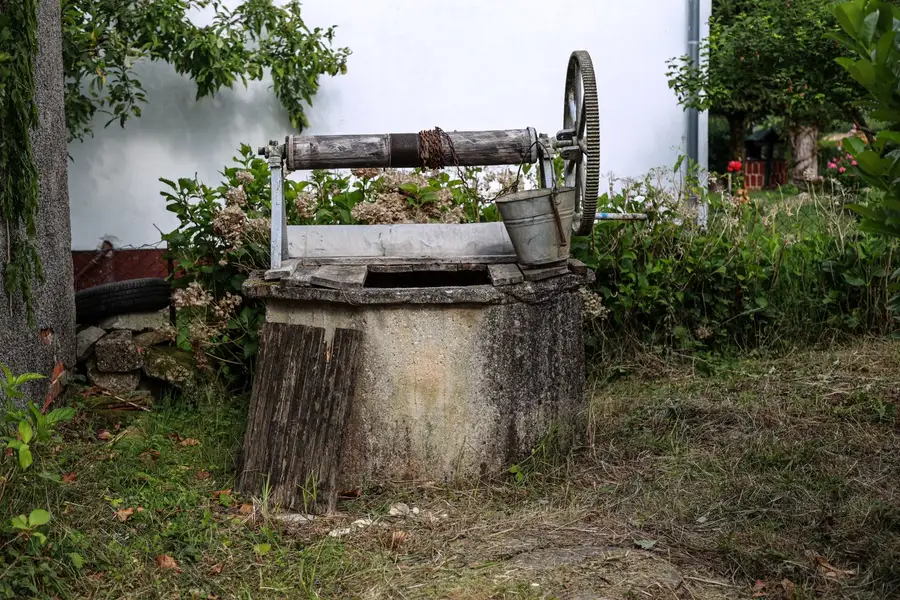 Poço antigo de pedra com balde, lembrança do trabalho noturno de Cleantes de Assos