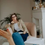 Psicóloga ouvindo uma paciente durante sessão de terapia num consultório claro