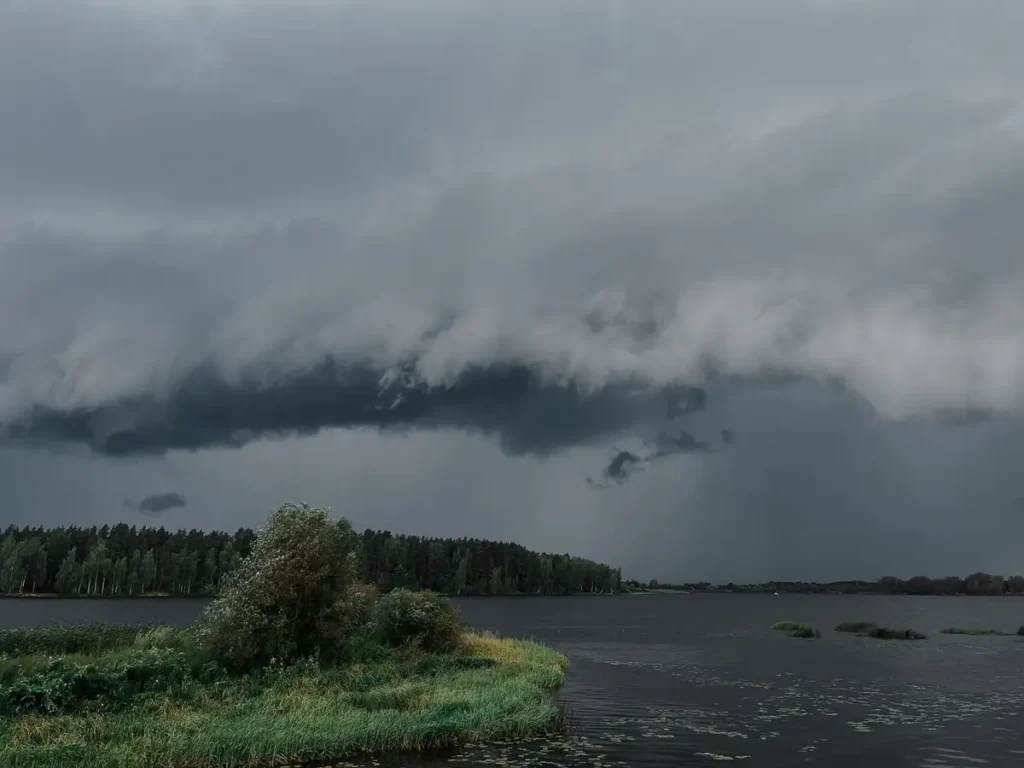 Nuvens de tempestade se formando sobre um lago calmo cercado de floresta