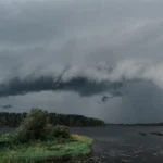 Nuvens de tempestade se formando sobre um lago calmo cercado de floresta